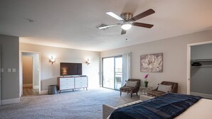 A spacious bedroom with a large bed, a ceiling fan, a TV, and a sliding glass door leading to a balcony. - Gated- LV Country Club Sleeps 8 (Las Vegas)