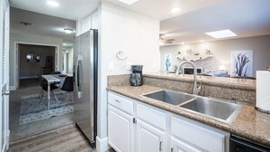 A modern kitchen with white cabinets, granite countertops, a stainless steel refrigerator, and a built-in sink. - Gated- LV Country Club Sleeps 8 (Las Vegas)
