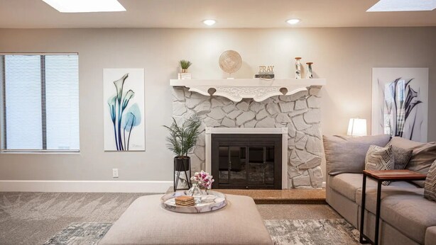 A living room with a stone fireplace, a sofa, a coffee table with a tray, and artwork on the walls. - Gated- LV Country Club Sleeps 8 (Las Vegas)