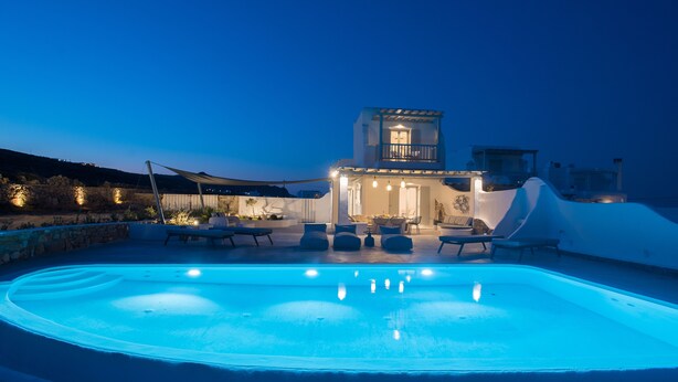 A swimming pool with lounge chairs and a building with a balcony. - 3-bed Villa in Mykonos With Private Pool (Mykonos)