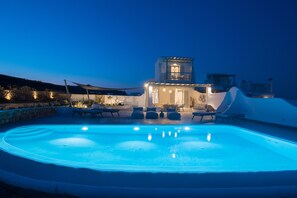 Une piscine avec des chaises longues et un bâtiment doté d’un balcon.