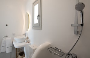 A modern bathroom with a white sink, mirror, and shower.
