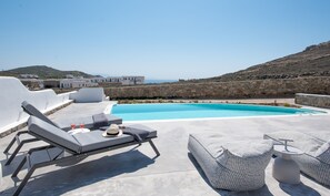 A rooftop pool area with lounge chairs and a stone wall.