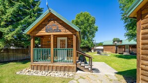 A wooden cabin with a porch, stone pathway, and a fenced yard. - Trapper cabin (Northport)