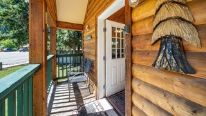 A wooden cabin with a porch, a door, and a bench. - Trapper cabin (Northport)