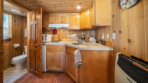 A wooden cabin interior with a kitchen area, including cabinets, a sink, and a stove. - Trapper cabin (Northport)