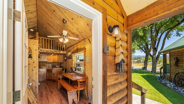 A wooden cabin interior with a kitchen, dining area, and a view of the outdoors. - Trapper cabin (Northport)