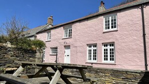A pink building with a stone wall, a wooden bench, and a stone staircase. - The Brewhouse Boscastle Harbour (Boscastle)