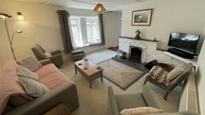 A living room with a sofa, armchairs, a coffee table, a fireplace, and a television. - The Brewhouse Boscastle Harbour (Boscastle)