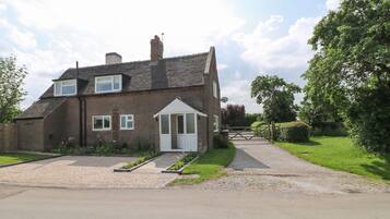 A two-story house with a front garden, a driveway, and a gated entrance.