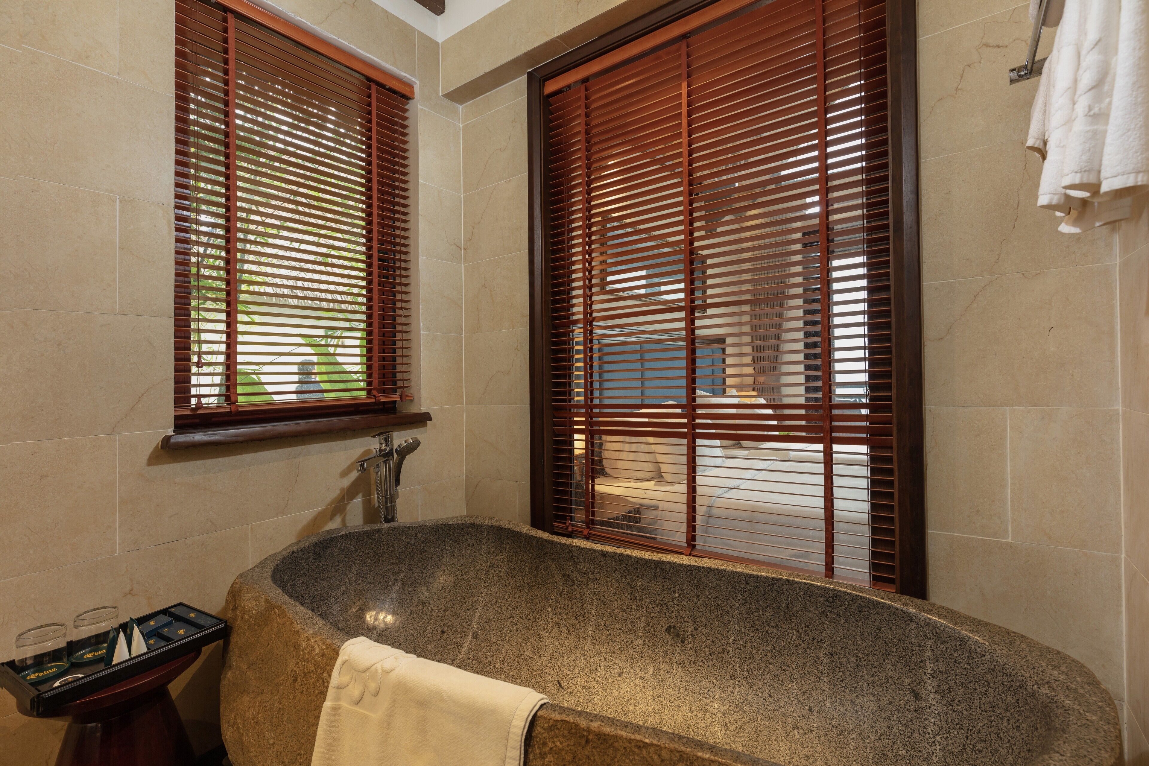 A bathroom with a freestanding bathtub, wooden blinds, and a towel rack.