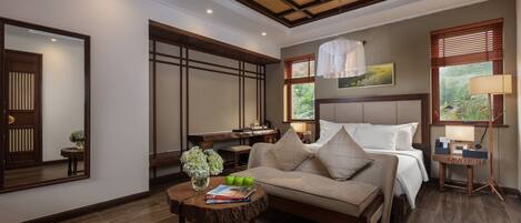A well-lit bedroom with a large bed, a desk, and a seating area with a coffee table.