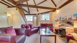 A cozy living room with a fireplace, leather sofas, and a staircase. - Grade II Old Engine House, on the SW Coast Path (Noss Mayo)