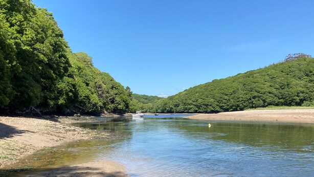 A river with clear water, surrounded by dense green forest and sandy banks. - Grade II Old Engine House, on the SW Coast Path (Noss Mayo)
