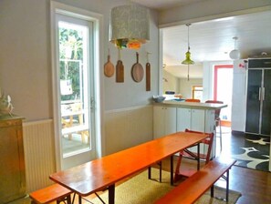 Enjoy casual meals and gatherings in this kitchen with a dining table and benches, and access to an outdoor space with a view of the surrounding greenery.