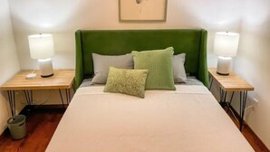 A neatly made bed with a green headboard, two bedside lamps, and a framed artwork above. - Lovely Home! Great Location! The Nature House (Springfield)