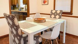 A dining area with a white table, patterned chairs, a wooden bowl centerpiece, and a kitchen in the background. - Lovely Home! Great Location! The Nature House (Springfield)