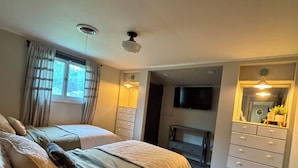 A bedroom with two beds, a dresser, a TV, and a mirror.