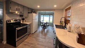 A modern kitchen with a stove, refrigerator, and dining area.