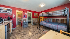 Ein kleines Zimmer mit Etagenbett, Küchenzeile und Essbereich.