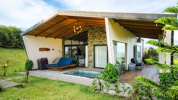 A modern house with a covered patio, a swimming pool, and a lush garden.