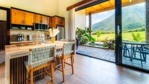 A modern kitchen with wooden cabinets, a built-in microwave, and a large island with bar stools. - Villas Jawara (La Fortuna)