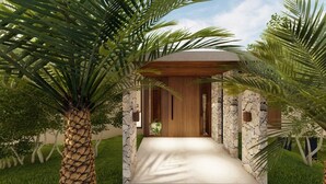 A modern building with a stone facade, a wooden entrance, and a covered walkway surrounded by palm trees. - Villas Jawara (La Fortuna)