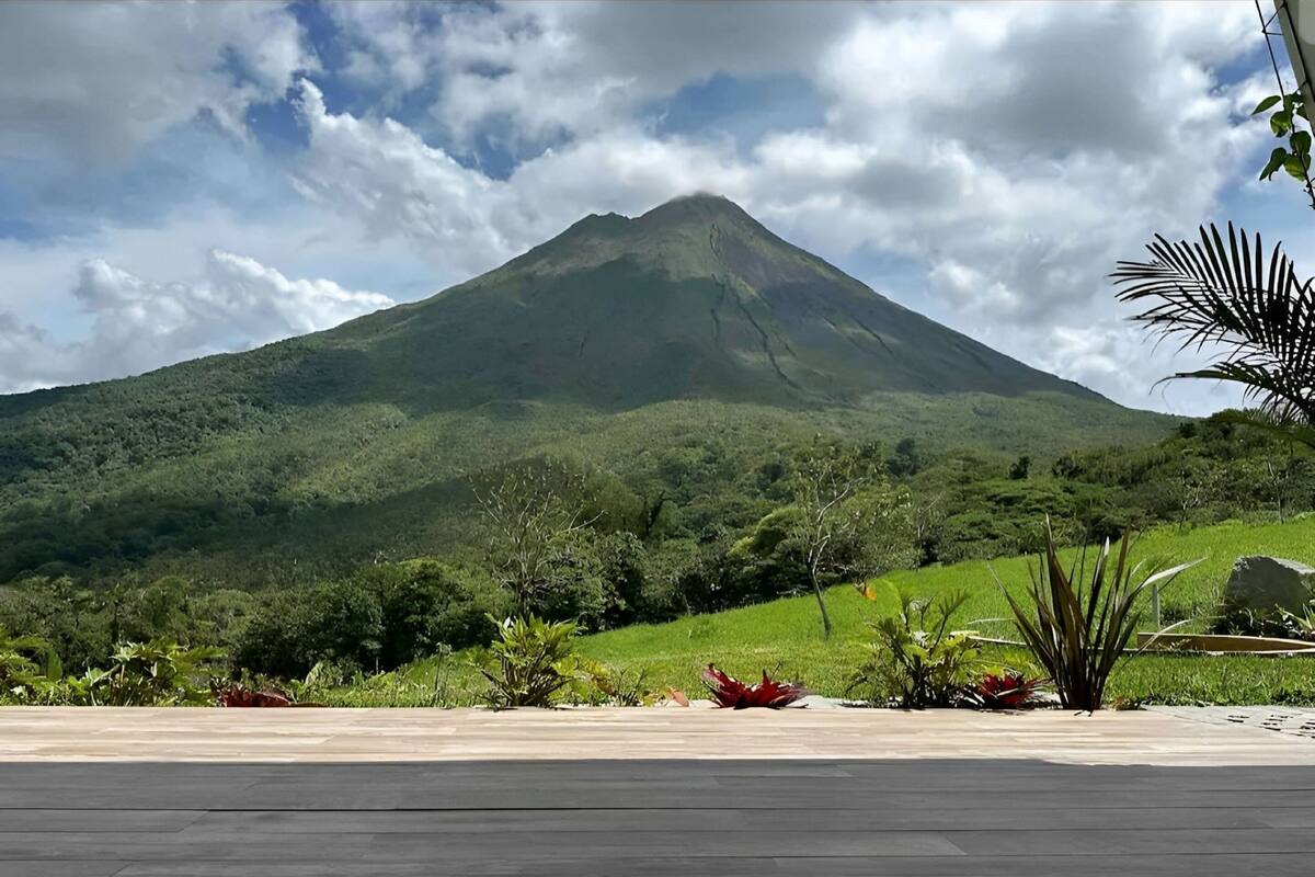 A view of a mountain with lush greenery and a paved area in the foreground.