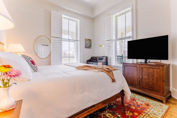 A bedroom with a bed, a television, a wooden cabinet, and a window.