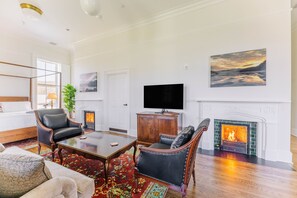 A spacious living room with a fireplace, a television, and a large painting on the wall.