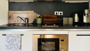 Une cuisine moderne avec des armoires blanches, un four en acier inoxydable, une machine à café et un évier.