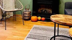 Un salon avec une cheminée, une table ronde, une chaise et un tapis.