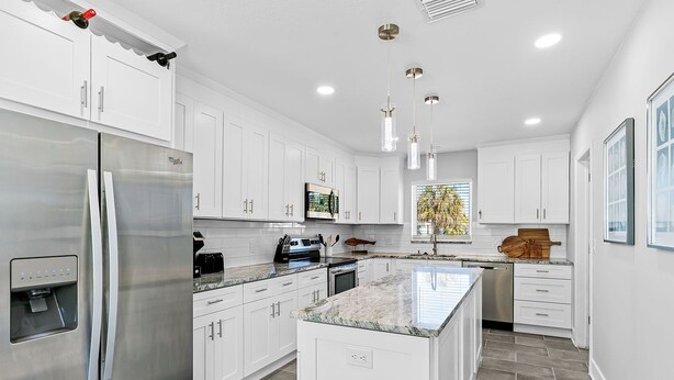 A modern kitchen with white cabinets, stainless steel appliances, and a granite countertop. - Amazing Home on the Intracoastal Waterway! (Indian Rocks Beach)