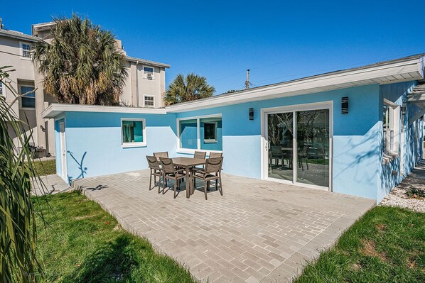 A modern house with a patio, a dining table, and a large sliding glass door. - Amazing Home on the Intracoastal Waterway! (Indian Rocks Beach)