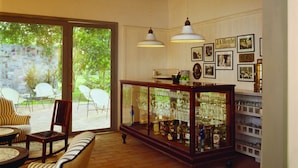 A spacious room with a wooden ceiling, a bar area with a glass display case, and a seating area with a sofa and chairs. - Maison Couturier, San Rafael, a Member of Design Hotels (San Rafael)