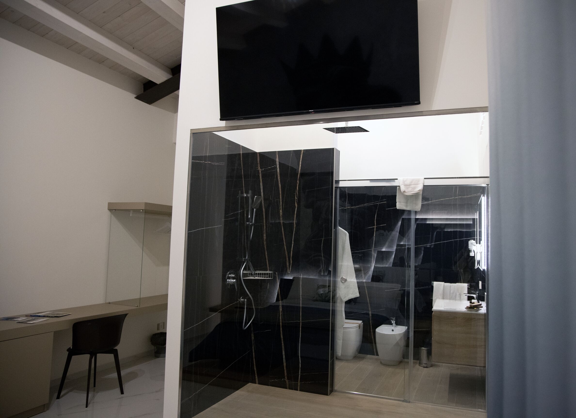 A modern bathroom with a glass-enclosed shower, a toilet, and a sink.