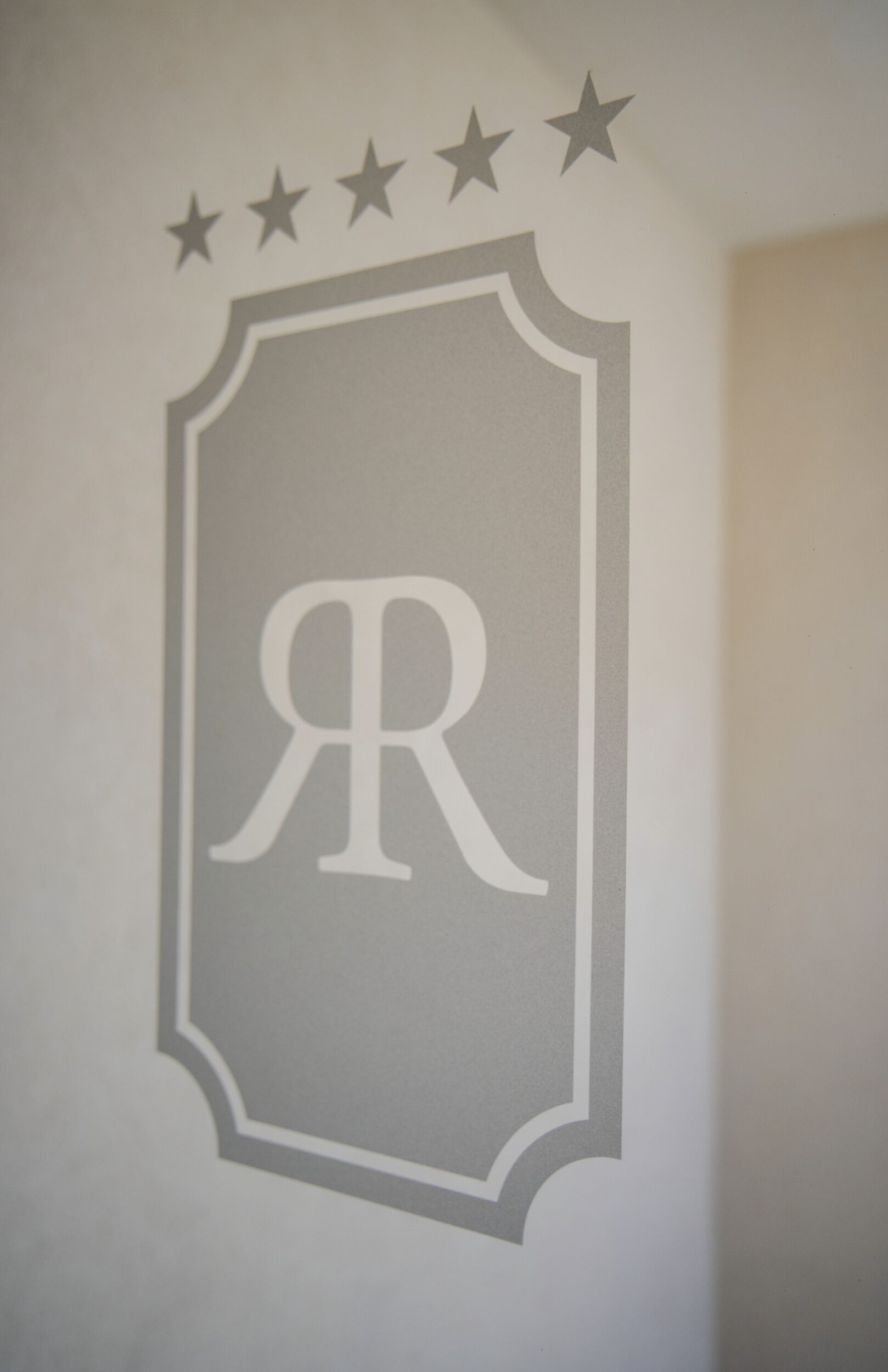 A wall decal with a shield shape, a central letter 'R', and four stars above it.