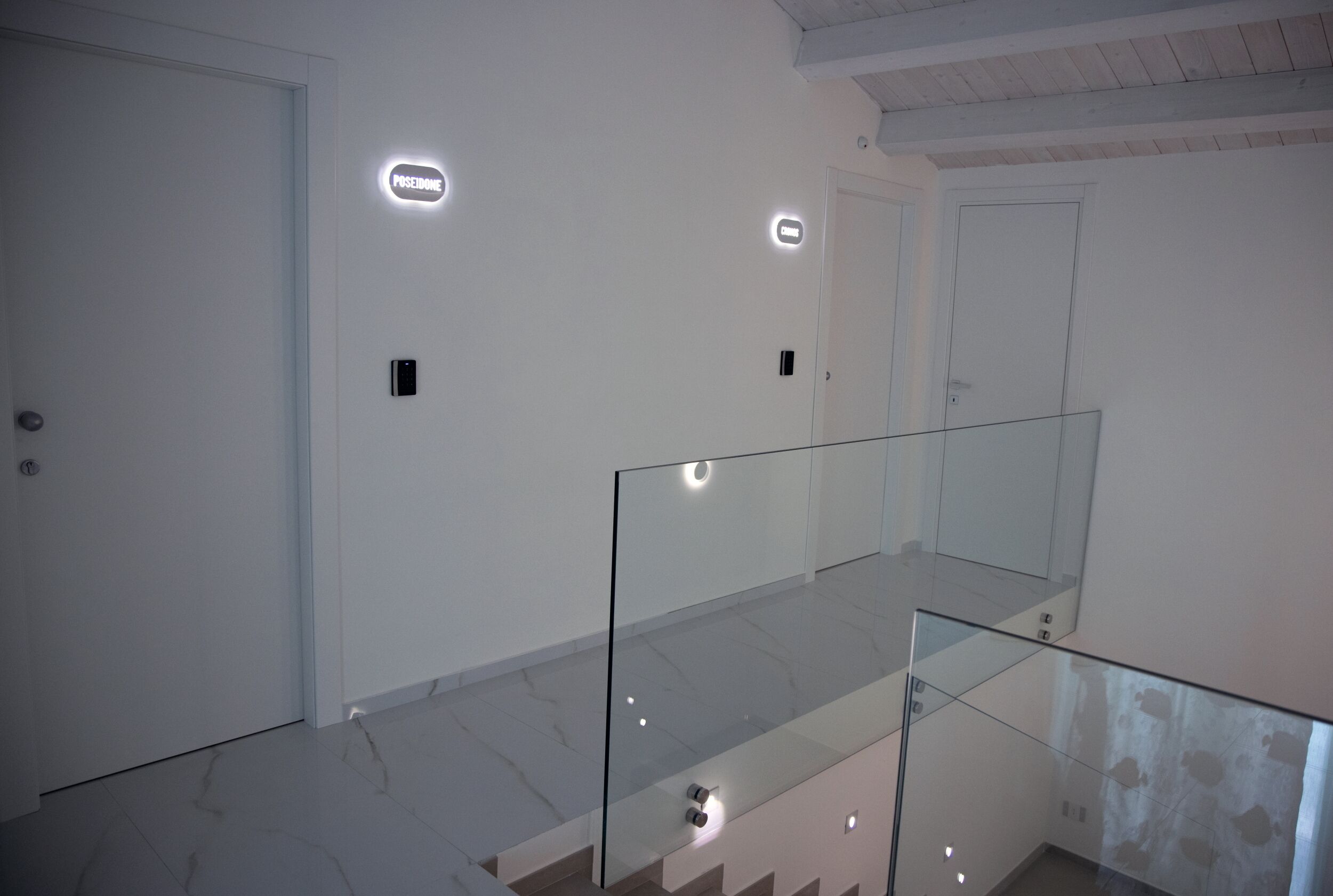 Un intérieur moderne avec une balustrade en verre, des murs blancs et un sol en marbre.