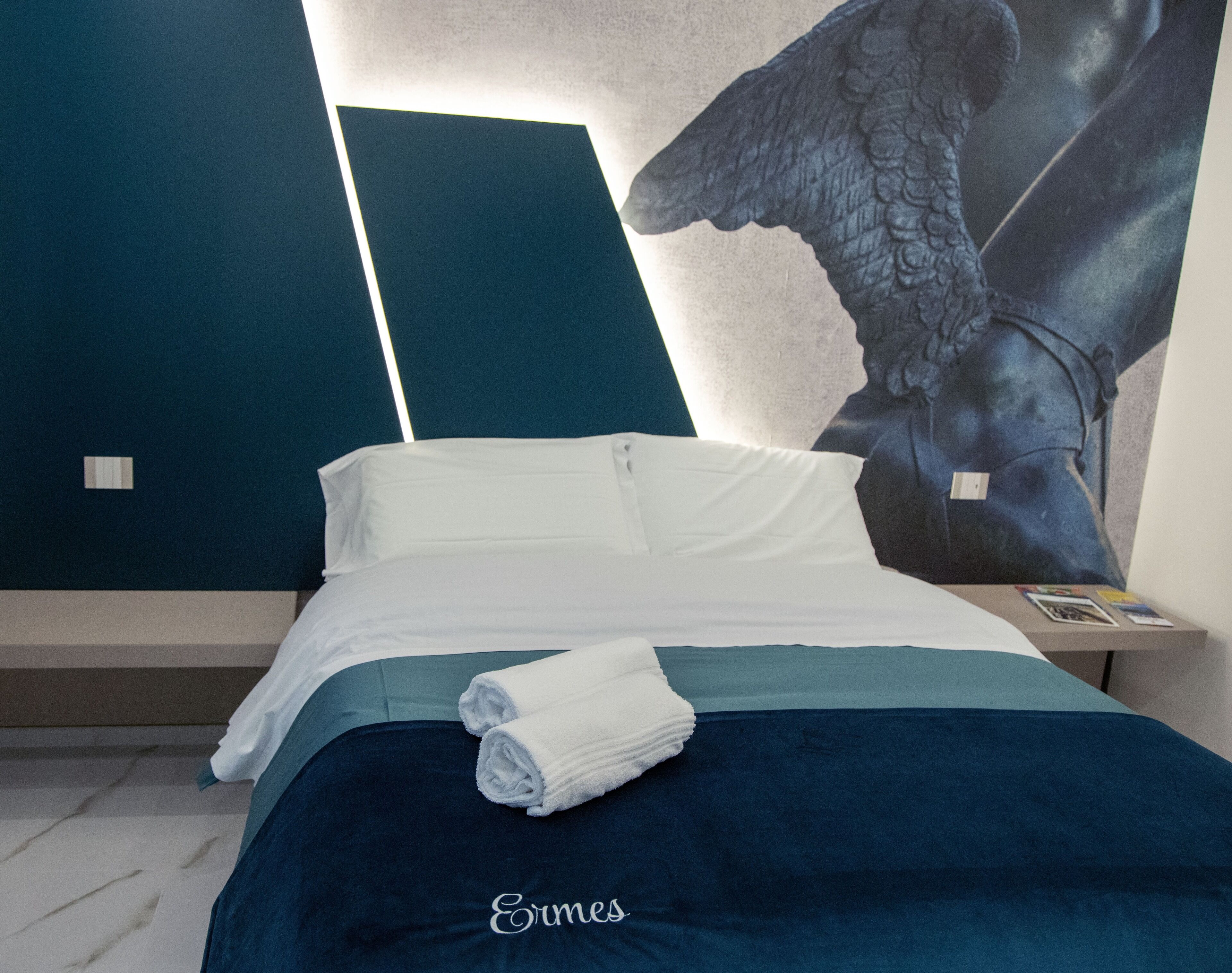 Une chambre d’hôtel avec un lit, une table de chevet et une grande fresque murale.