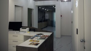 A modern hotel lobby with a reception desk, a computer, and a magazine rack. - Lauria Luxury Room (Gela)