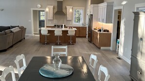 A spacious kitchen with wooden cabinets, a central island, and pendant lighting. - New Maine Private Lake House (Waltham)