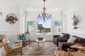 Un salón con una araña, muebles de mimbre y obras de arte en las paredes.