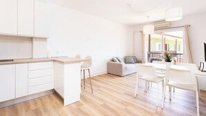 Eine moderne Küche mit weißen Schränken, einer Holzarbeitsplatte und einem Essbereich mit weißen Stühlen und einem Tisch.