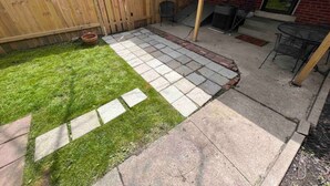 A backyard with a wooden fence, a patio area with stone tiles, and a grassy lawn. - 886 Macon (2 bdrm) · Walkable German Village home w/ fenced yard (Columbus)