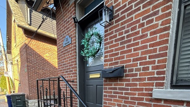 A brick building with a black front door, a mailbox, and a small step leading to the entrance. - 886 Macon (2 bdrm) · Walkable German Village home w/ fenced yard (Columbus)