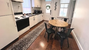 A kitchen with white cabinets, a black stove, and a round wooden table with four chairs. - 886 Macon (2 bdrm) · Walkable German Village home w/ fenced yard (Columbus)