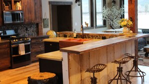 Une cuisine avec des meubles en bois, un four à micro-ondes, une cuisinière et un grand îlot central doté de tabourets de bar.