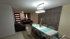 A dining area with a table set for four, a sofa, and a decorative plant.