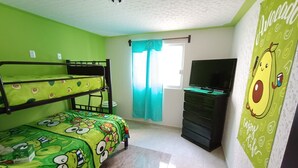 A room with bunk beds, a television, a dresser, and a wall with a fruit-themed mural.