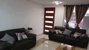 A living room with two dark leather sofas, a wooden coffee table, and a small side table with a basket.